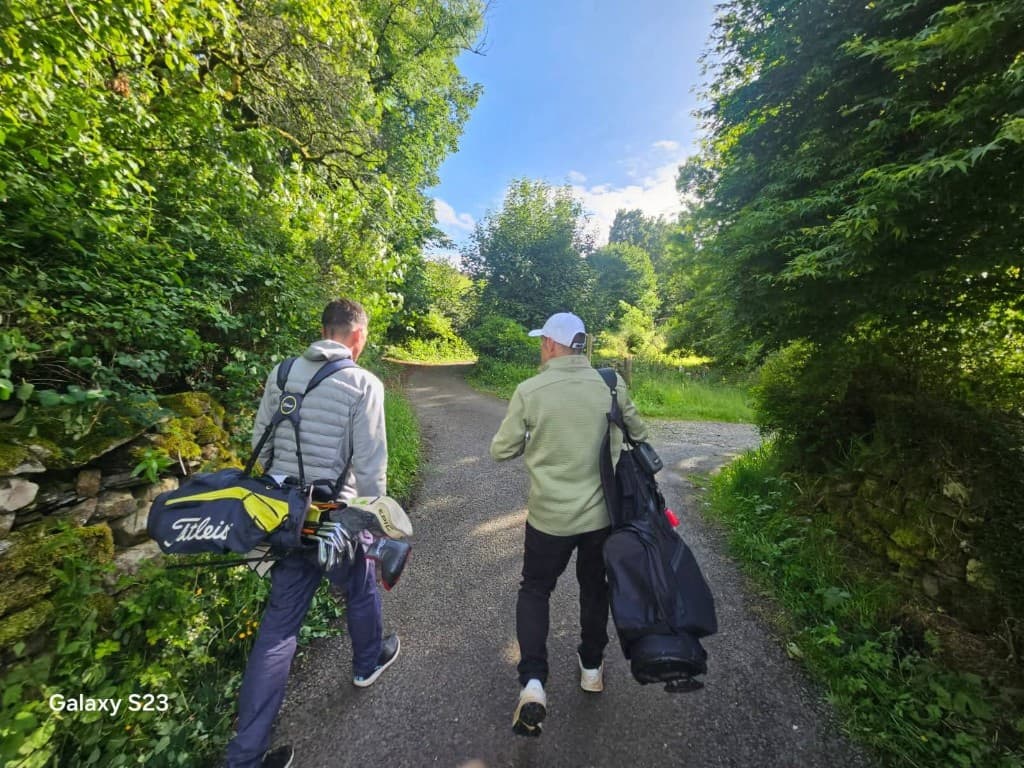 Two golfers walking along a course